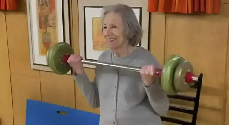 Beverly, 70, lifting weights confidently at home after transforming her balance and strength.