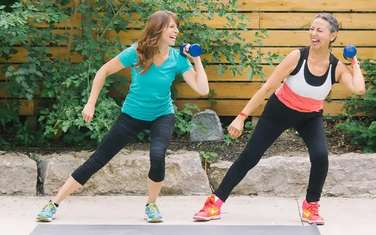 Senior woman strength training with dumbbells and Vintage Fitness personal trainer for weight loss in Toronto home