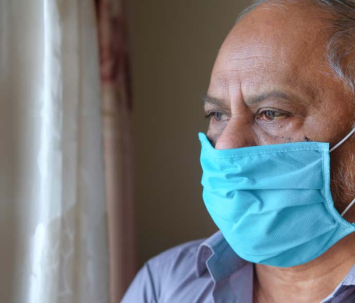 Senior using mask and staying by the window during the pandemic